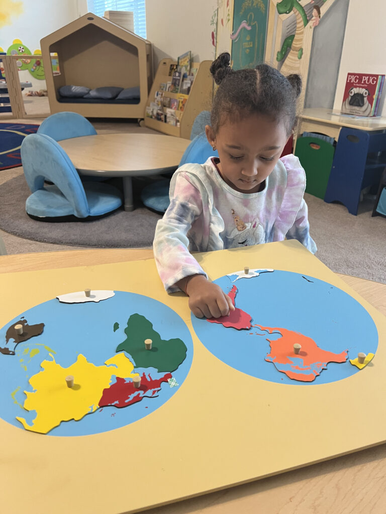 A young girl explores a globe in a Montessori classroom, engaging with her surroundings and learning about the world.