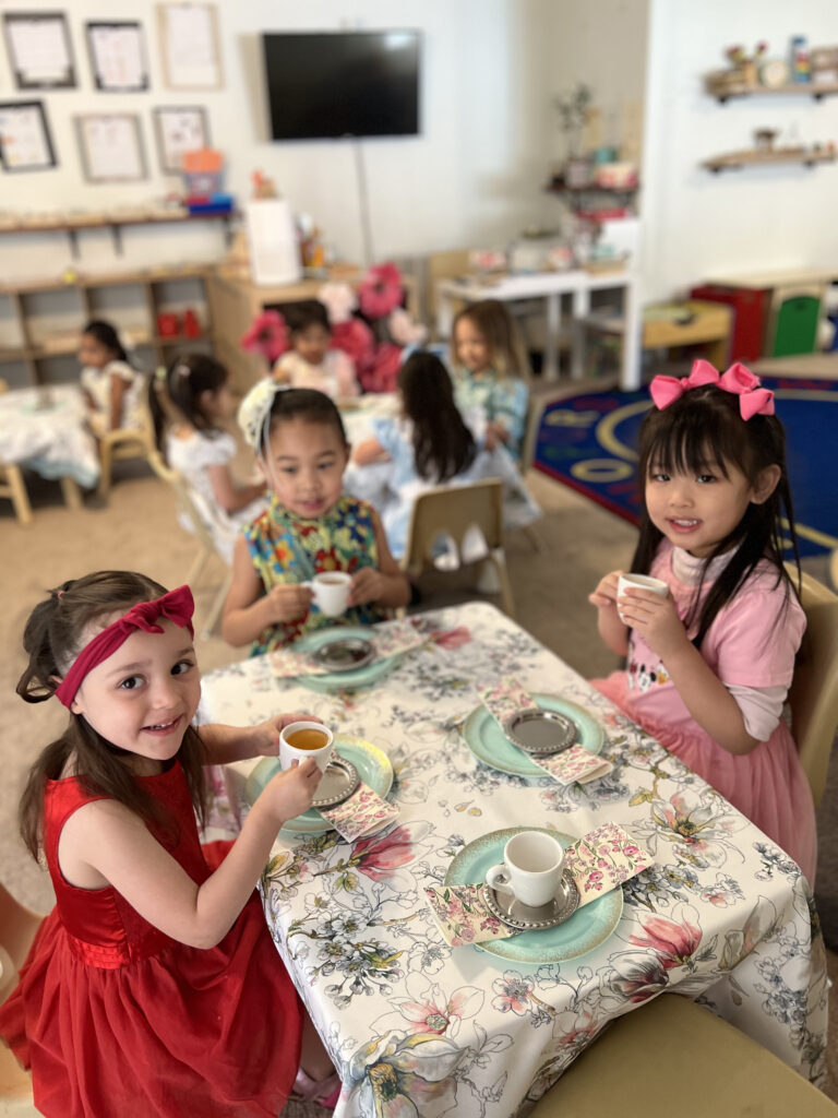 Little girls enjoying a tea party at a Montessori Education Daycare, surrounded by colorful decorations and playful tableware.